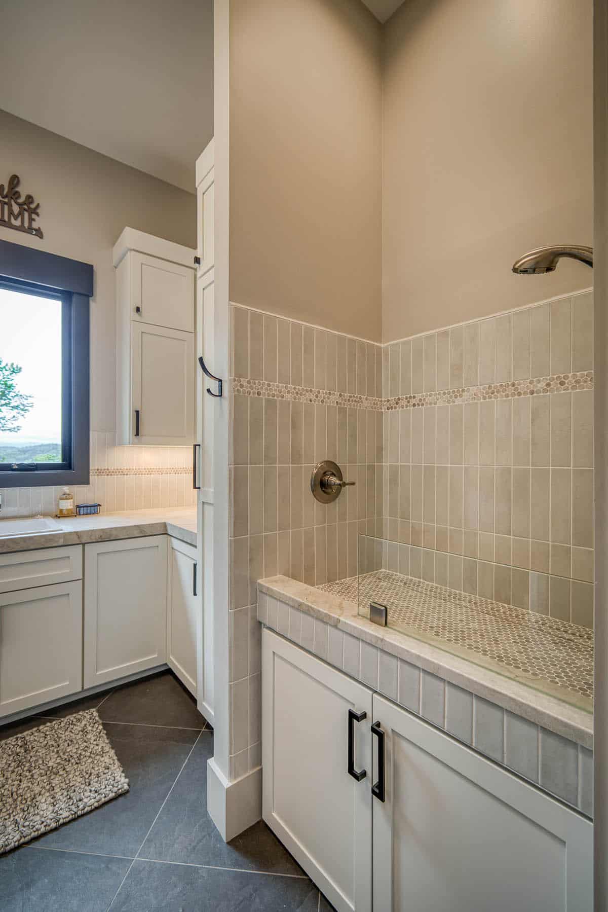 Dog wash station with tiled walls and handheld shower sprayer beside laundry room