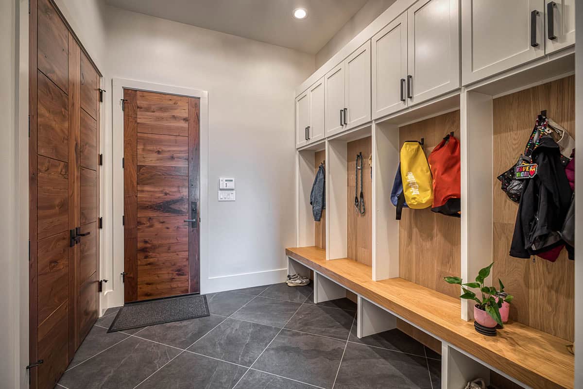 Mudroom with wood locker cubbies, bench seating, and walnut front door