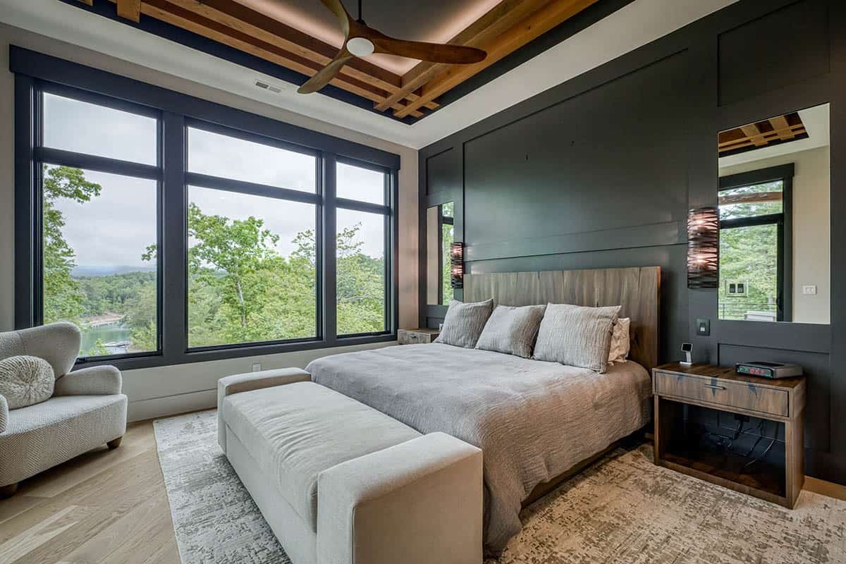 Bedroom with dark accent wall, wood headboard, large windows, and lake view