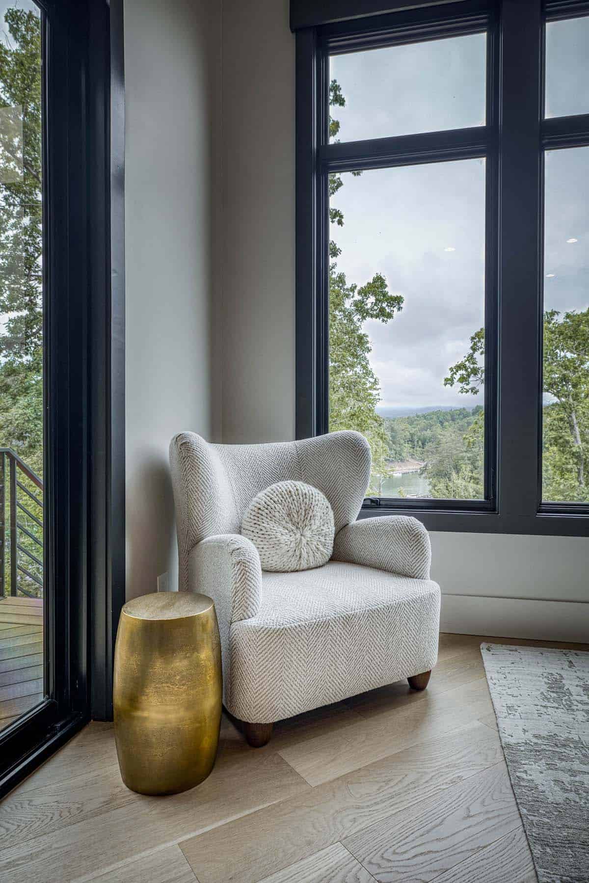 Cozy reading chair with round pillow in window nook overlooking the lake