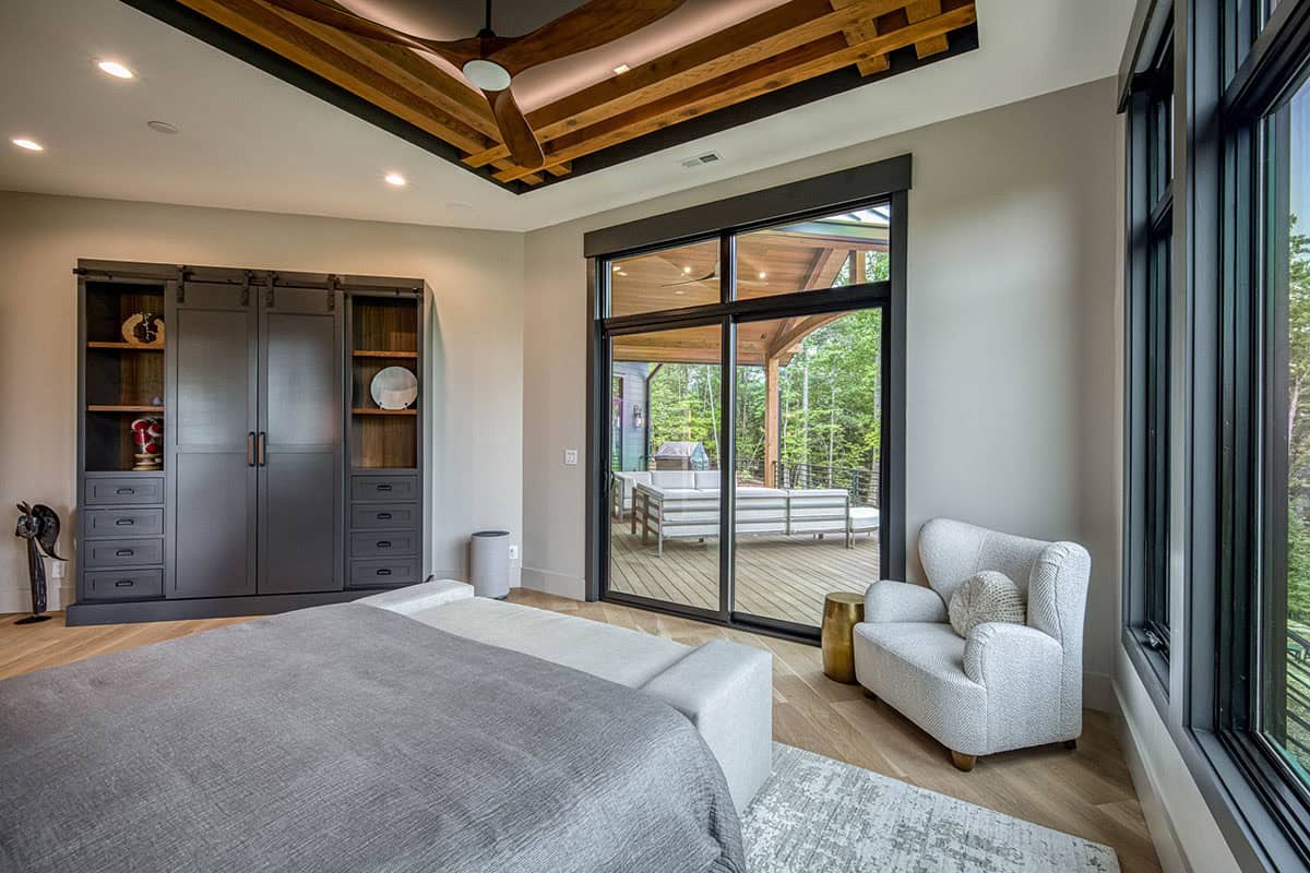 Bedroom with wood beam ceiling detail, built-in cabinetry, and sliding door to covered deck