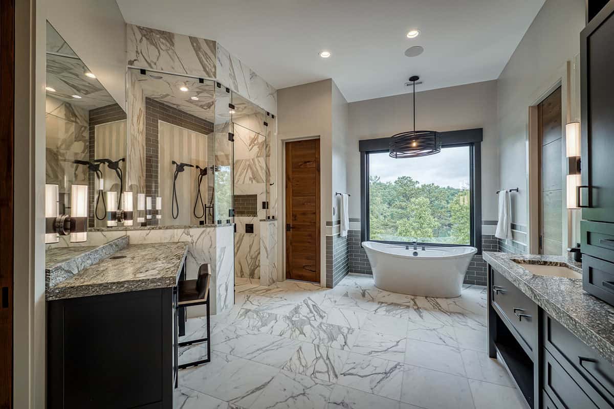 Primary bathroom with marble tile, glass shower, and freestanding tub by window