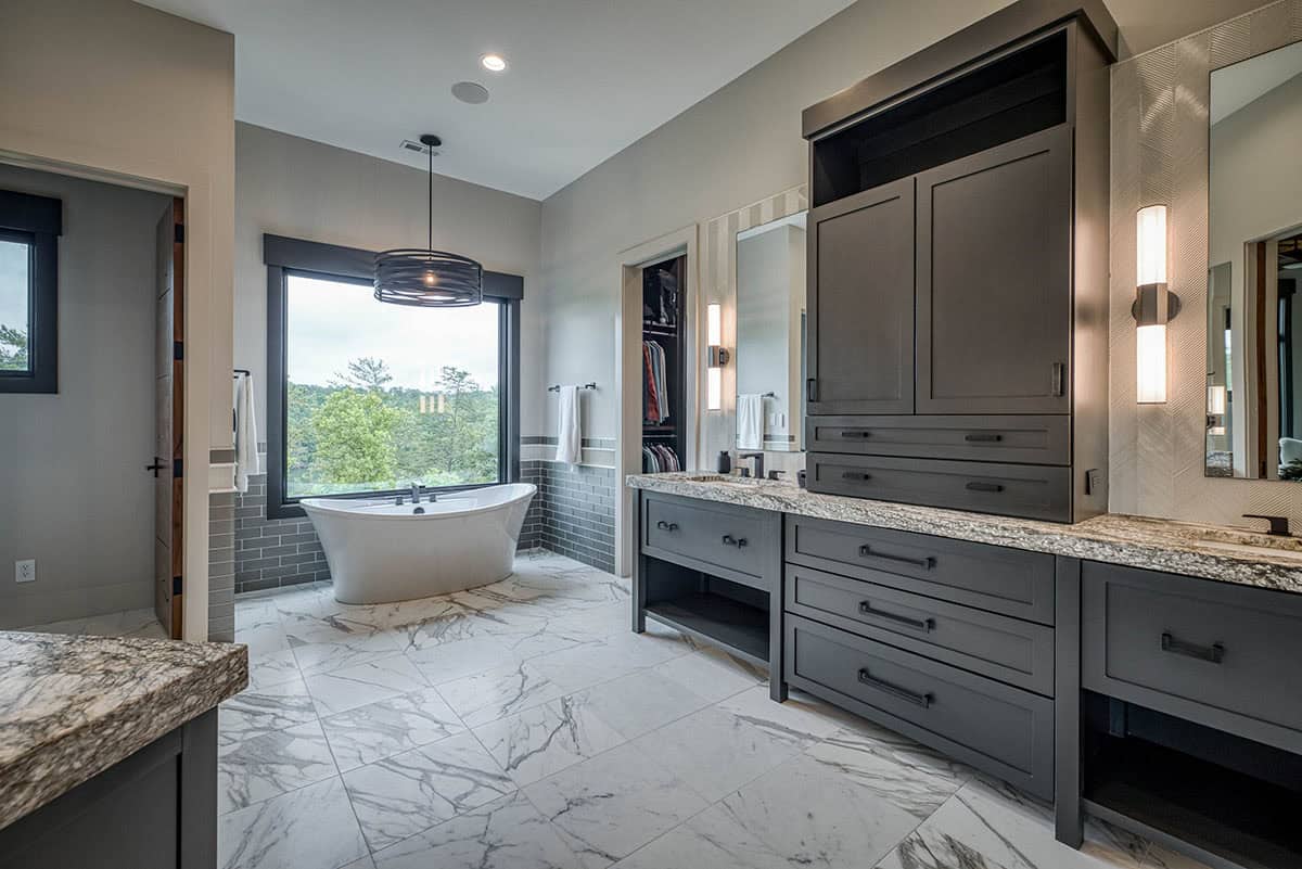 Primary bathroom with dark vanity cabinetry, marble floors, and freestanding soaking tub