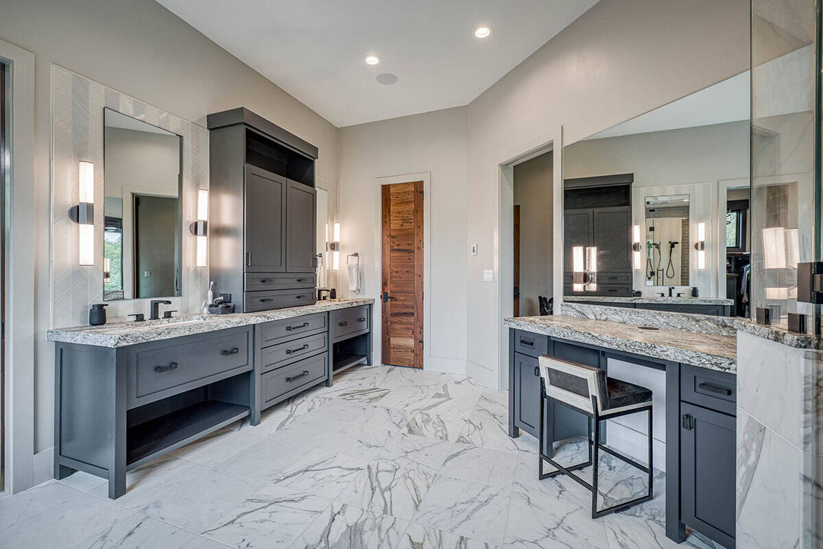 Double vanity bathroom with dark cabinetry, marble countertops, and makeup desk