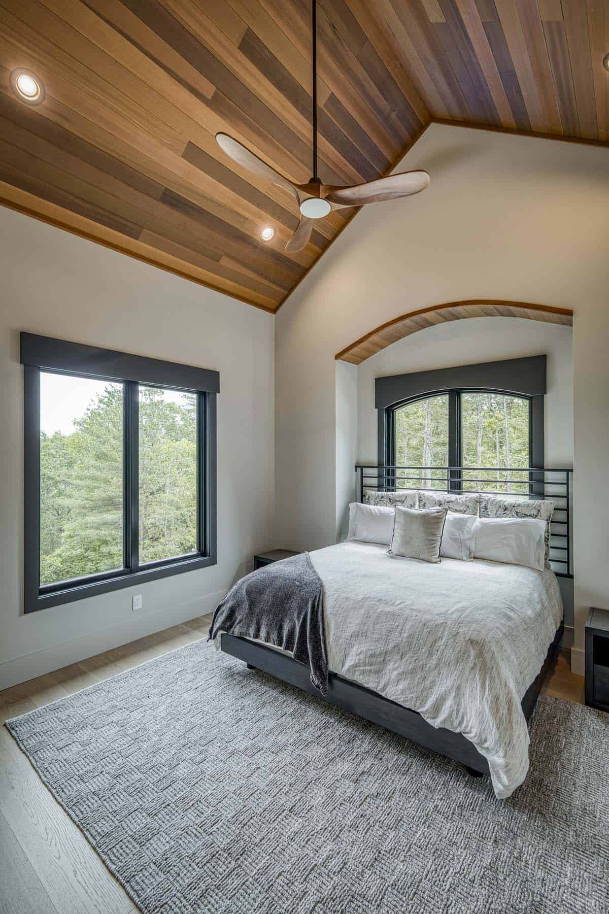 Bedroom with angled wood-clad ceiling, ceiling fan, and arched window nook