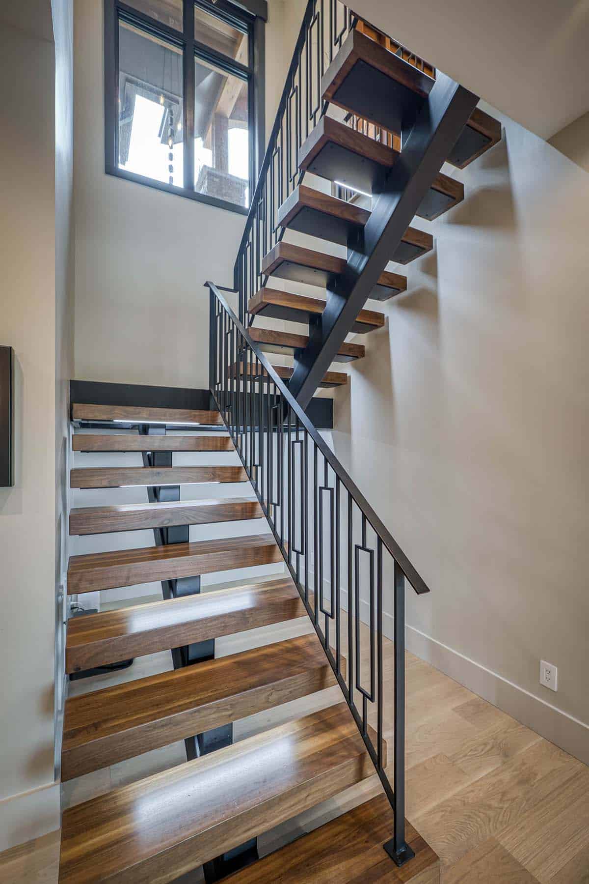 Close-up of floating wood staircase with black metal railing and glass-front treads