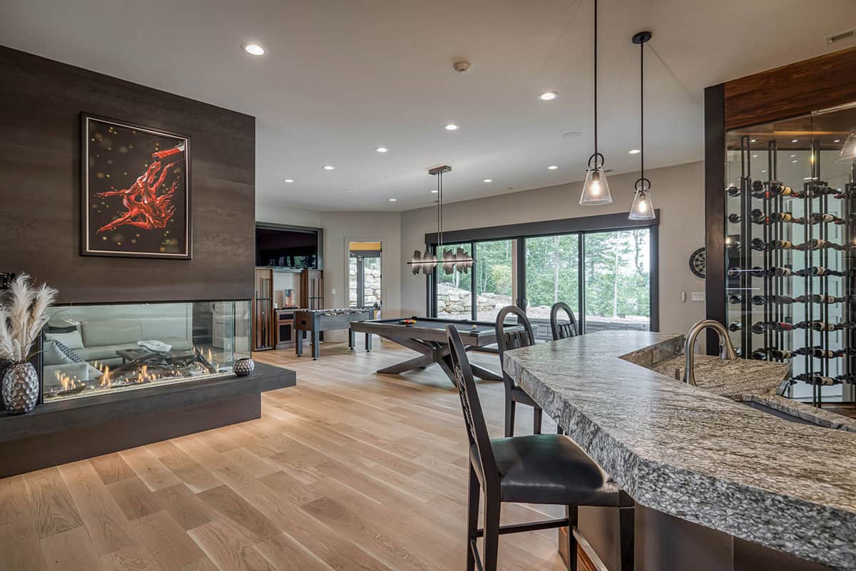 Lower-level lounge with three-sided fireplace, pool table, foosball, and wine display