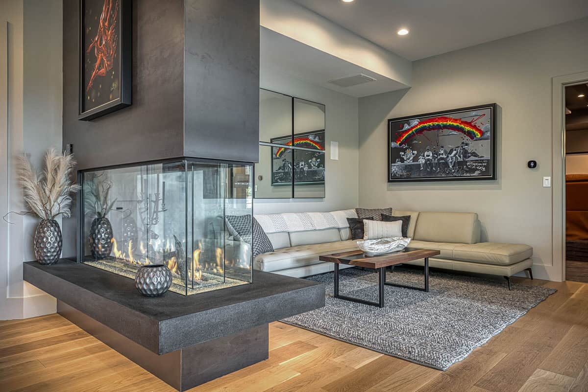 Living area with three-sided fireplace, leather sectional, and colorful framed artwork