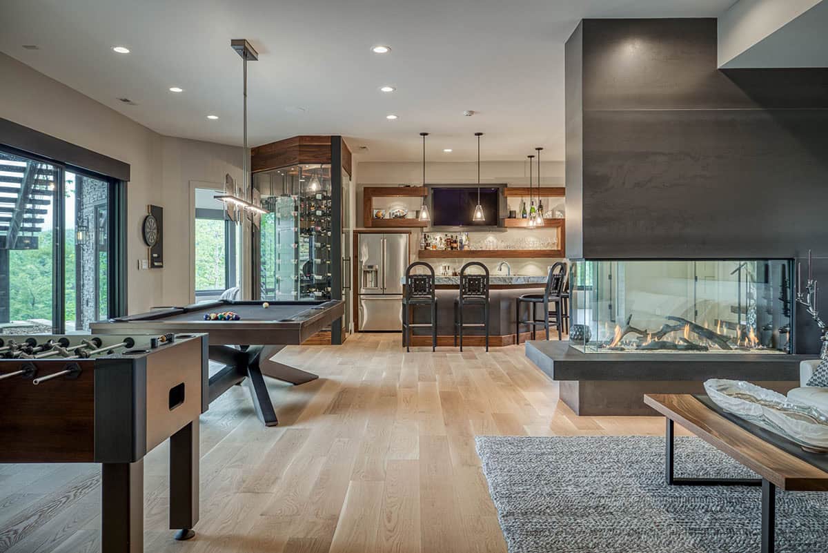 Game room with pool table, foosball table, wine display, bar seating, and three-sided fireplace