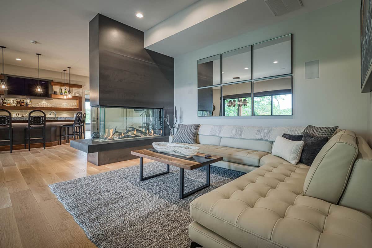 Leather sectional sofa facing three-sided fireplace with wine bar visible in background