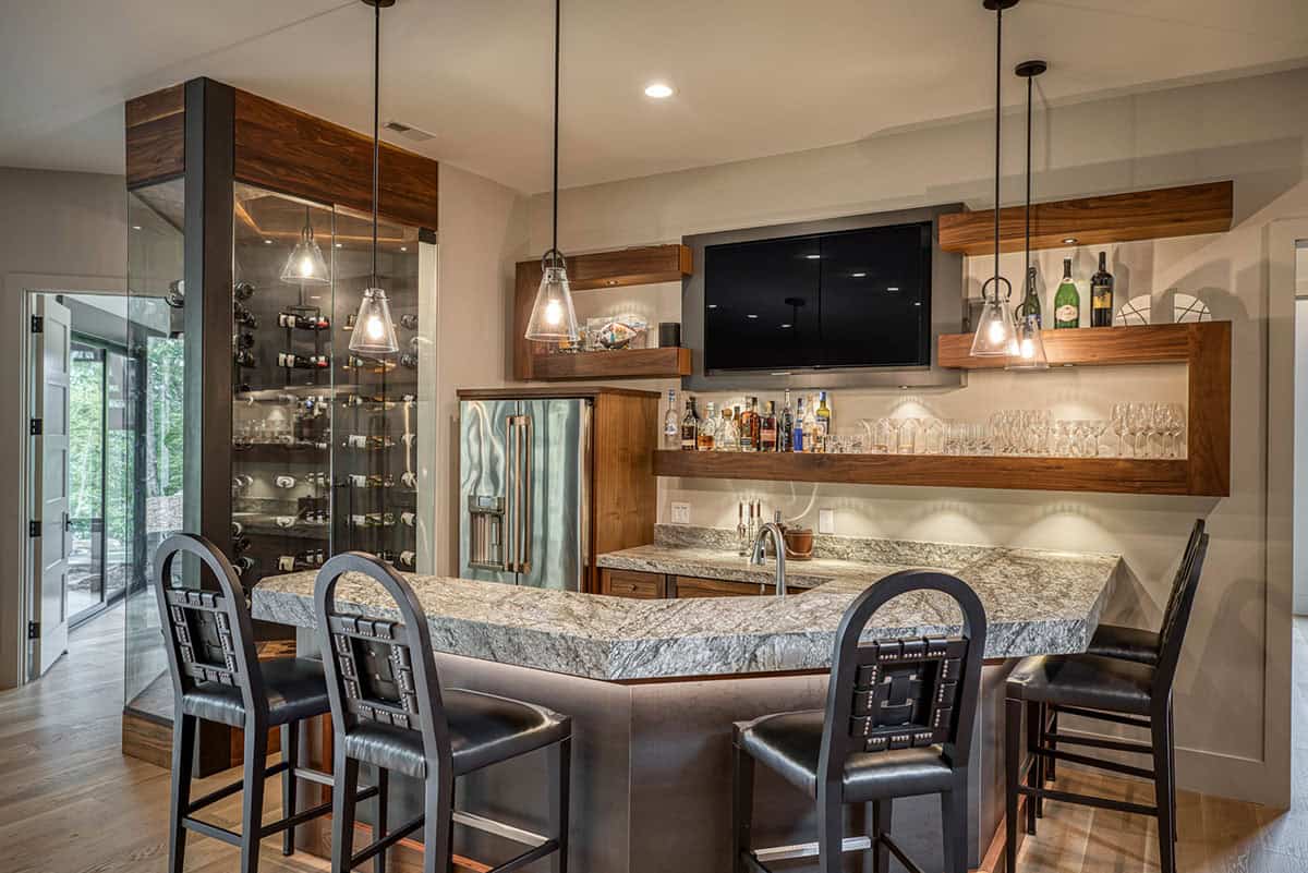 Wet bar with granite countertop, bar stools, TV, and glass wine display column