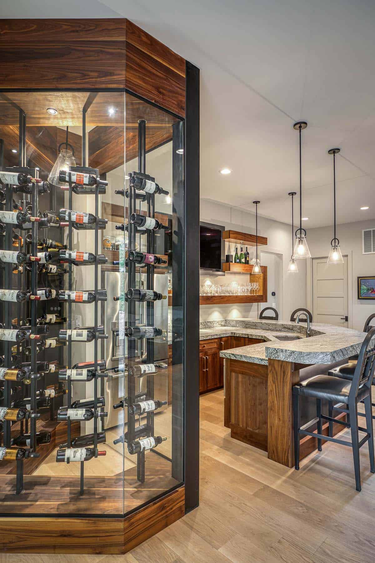 Corner wine display cabinet with wood trim opening onto bar and kitchen area