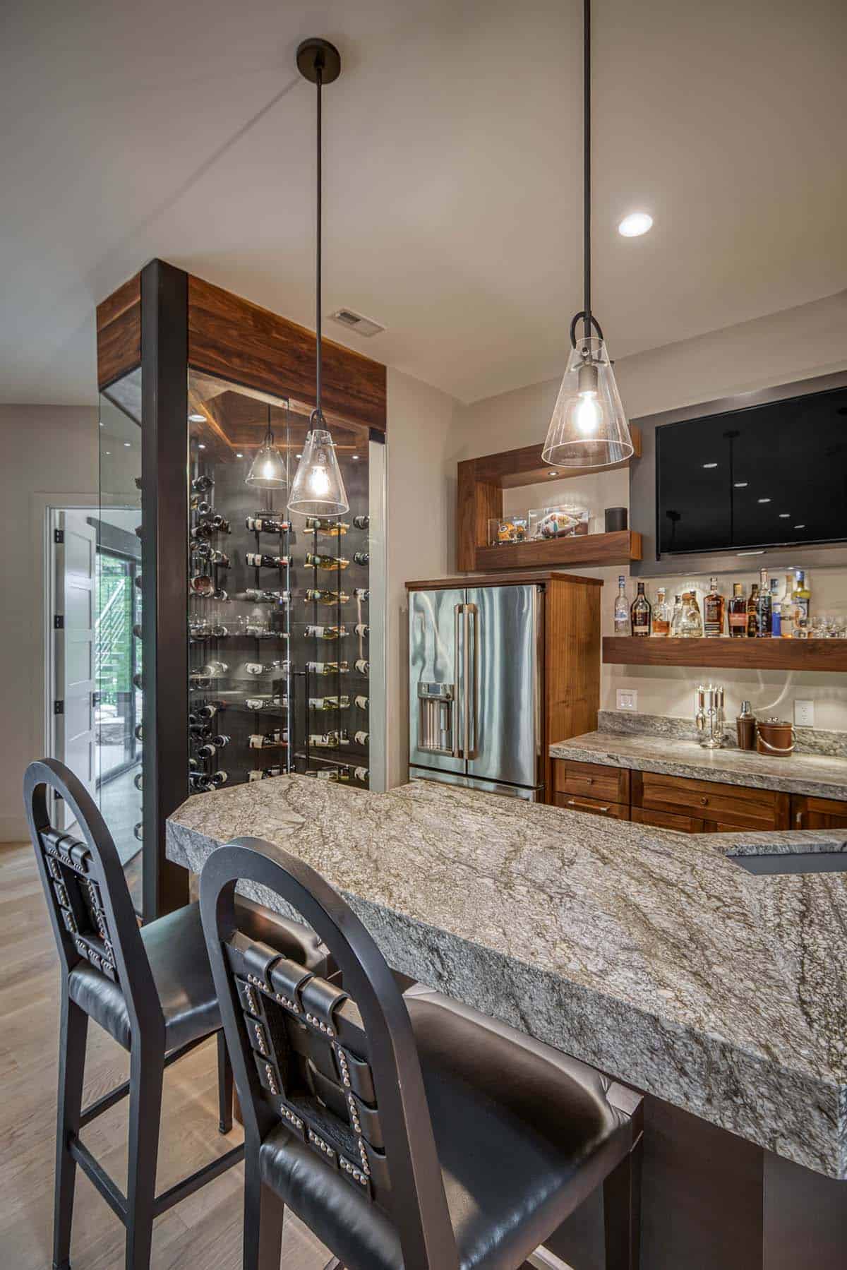 Bar counter view with wine display, stainless refrigerator, TV, and pendant lighting