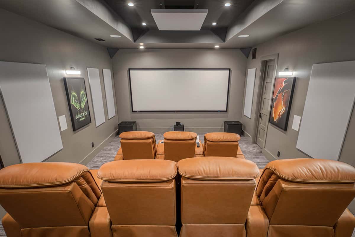 Home theater with orange leather reclining seats, large screen, and movie posters