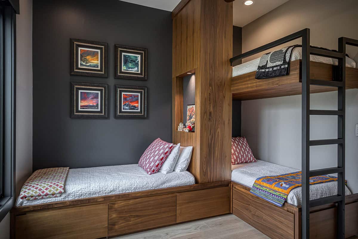 Close-up of built-in bunk beds and twin bed with dark accent wall and framed artwork