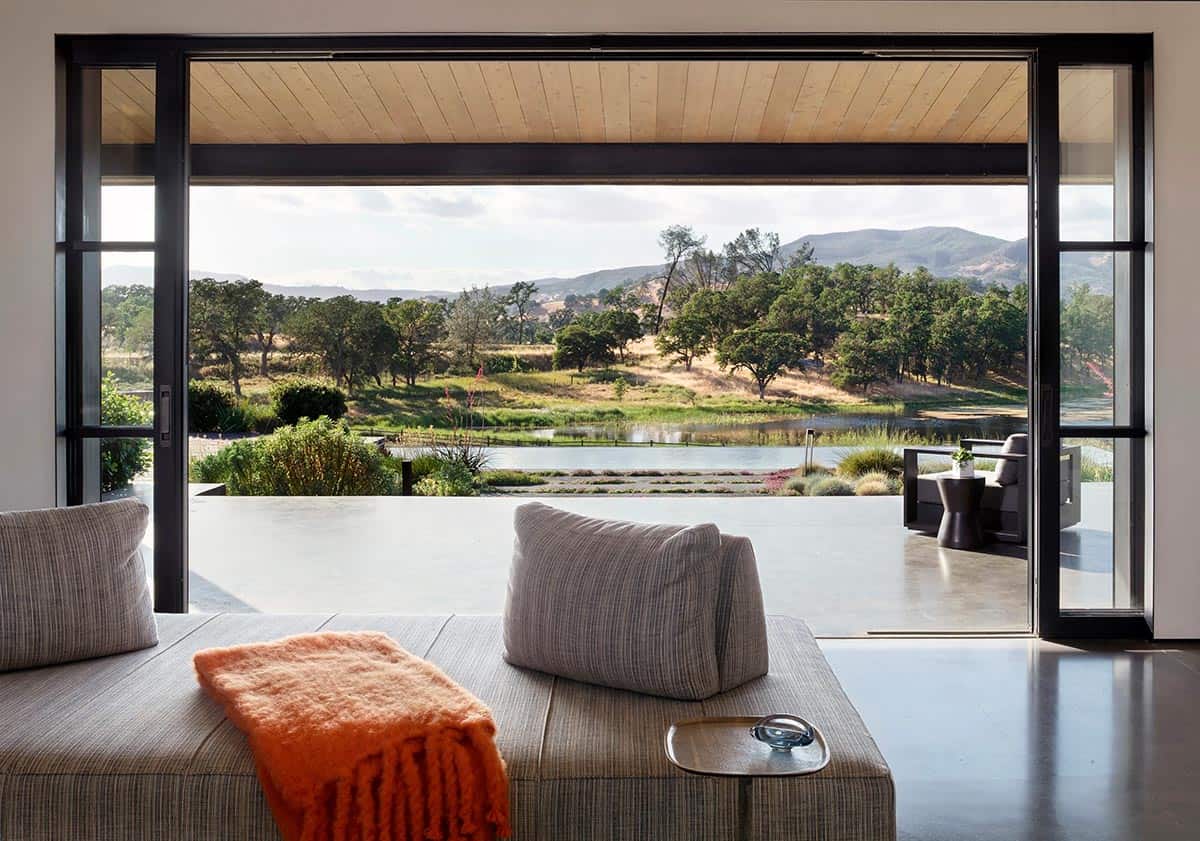 Living room daybed facing a wide sliding door with pond and mountain views