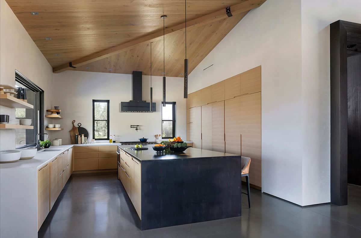 Kitchen with vaulted wood-clad ceiling, blackened steel island, and light oak cabinetry
