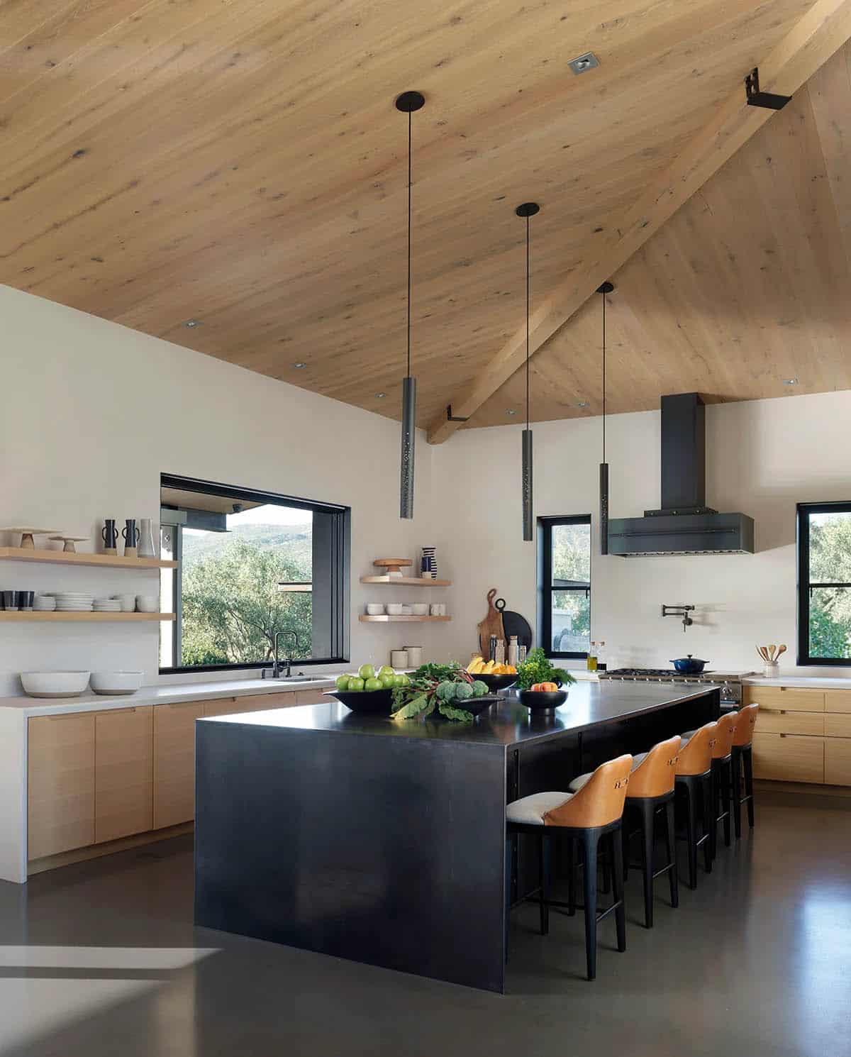 Kitchen island with leather barstools, pendant lights, and a vaulted timber ceiling