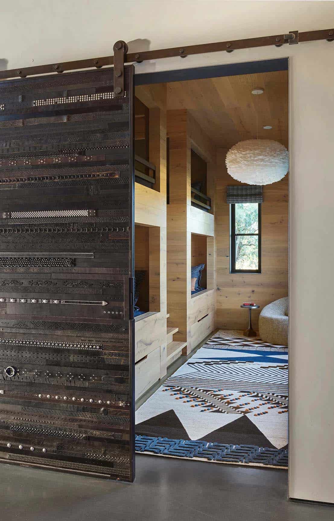 Studded leather sliding door open to a kids' bunk room with patterned rugs