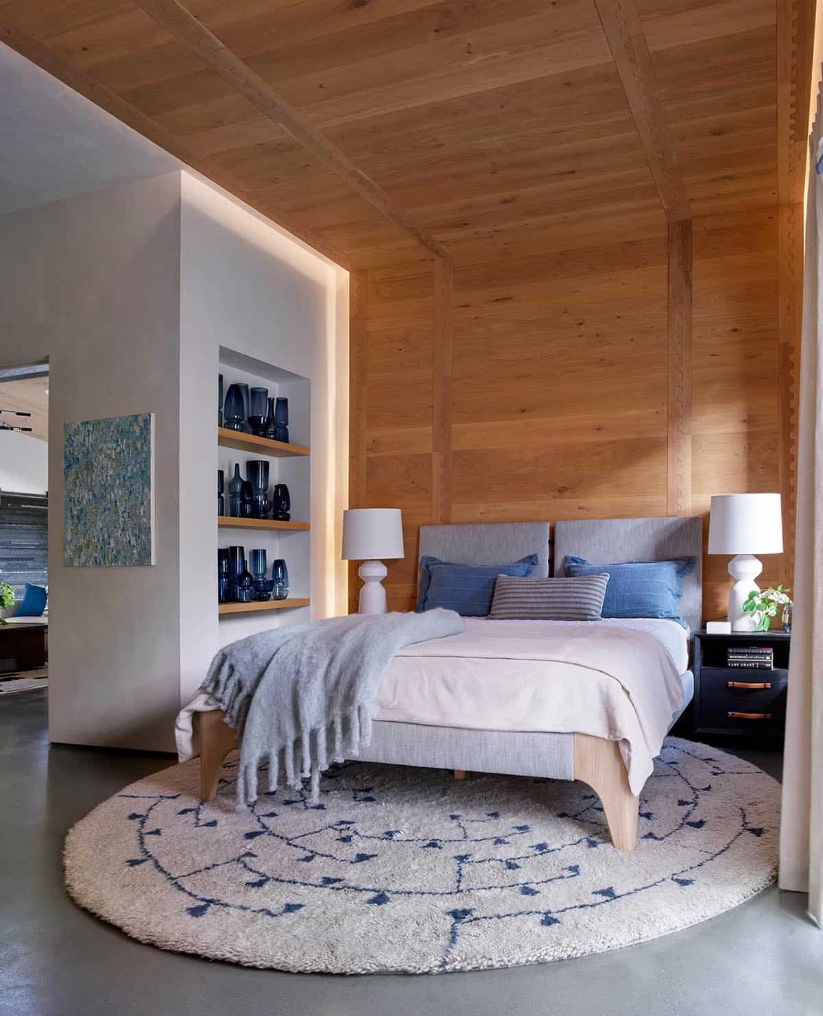 Wood-paneled bedroom nook with round patterned rug and built-in display shelving