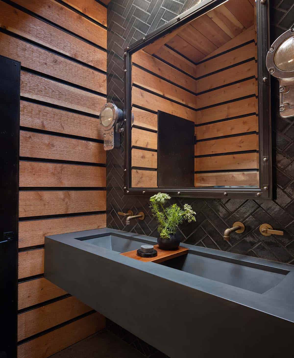 Rustic bathroom with black herringbone tile, wood slat walls, and industrial sconces