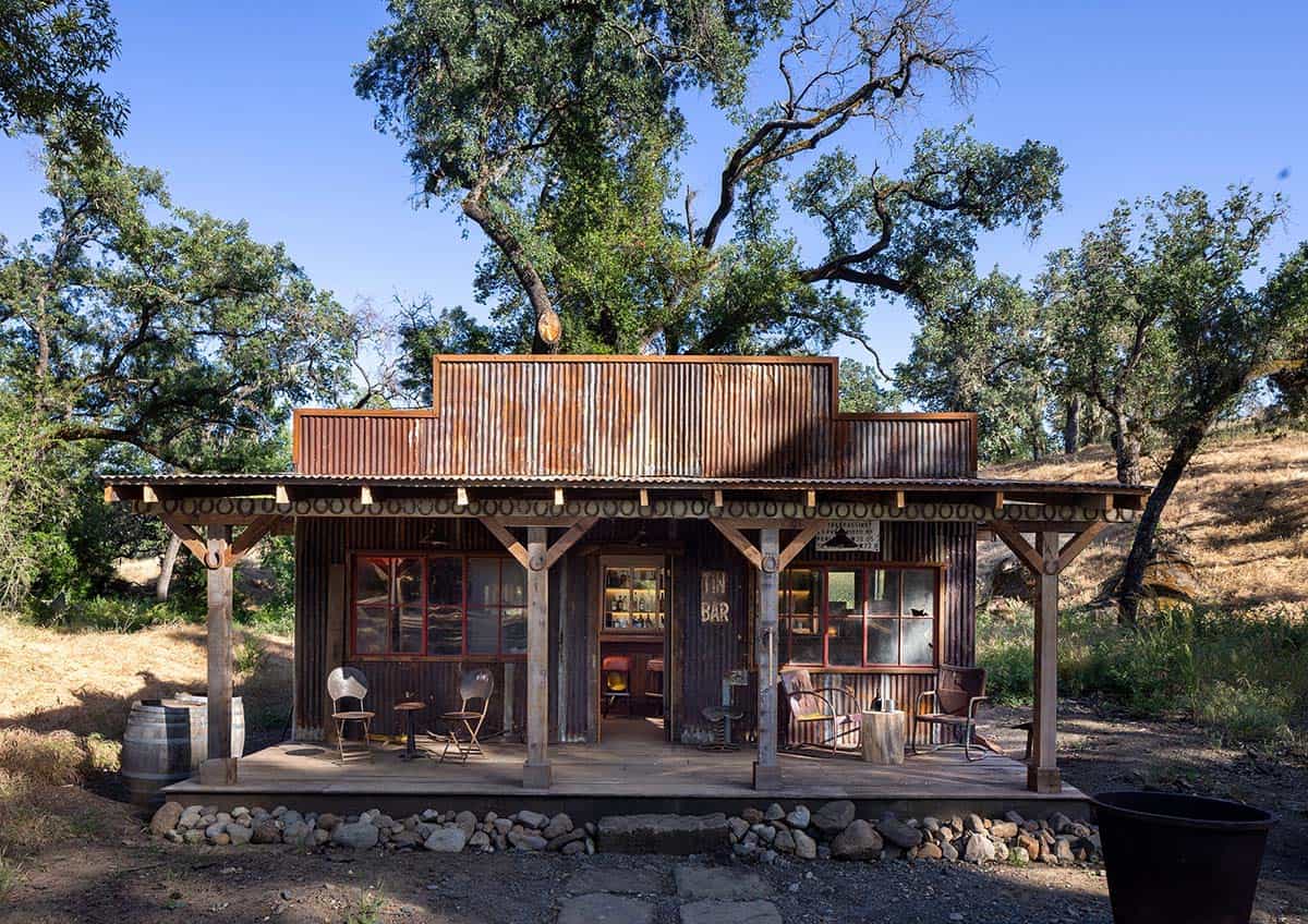 Rustic corrugated-metal "Tin Bar" cabin tucked beneath oak trees