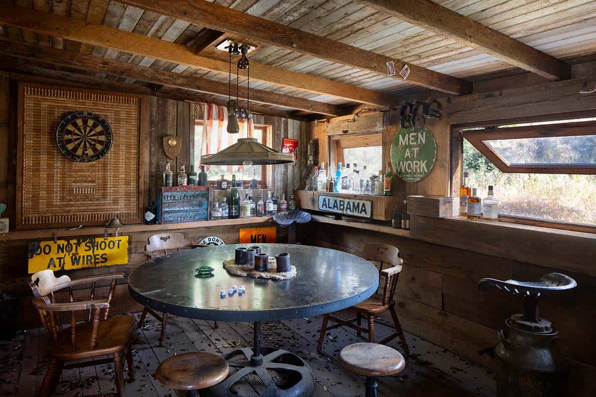 Weathered game room with round metal table, dartboard, and vintage signage