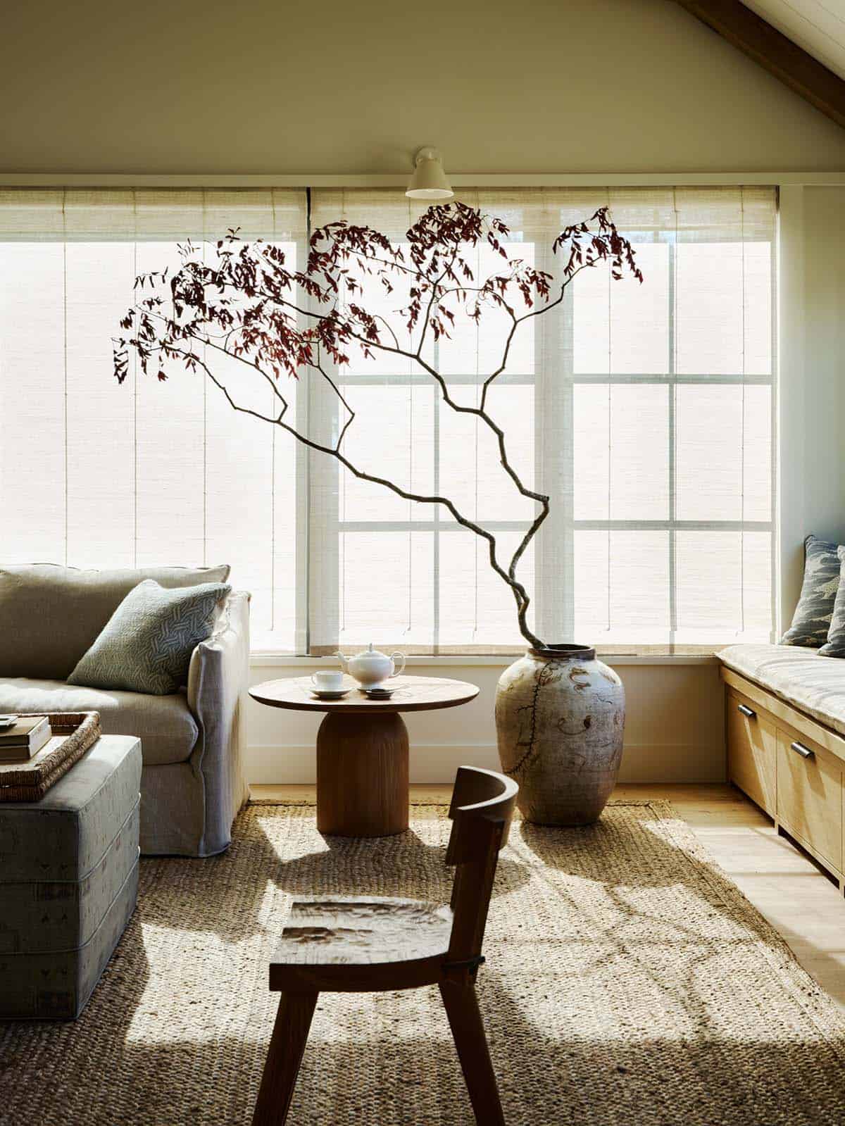 living room corner with rattan chair and faux branches in ceramic vase