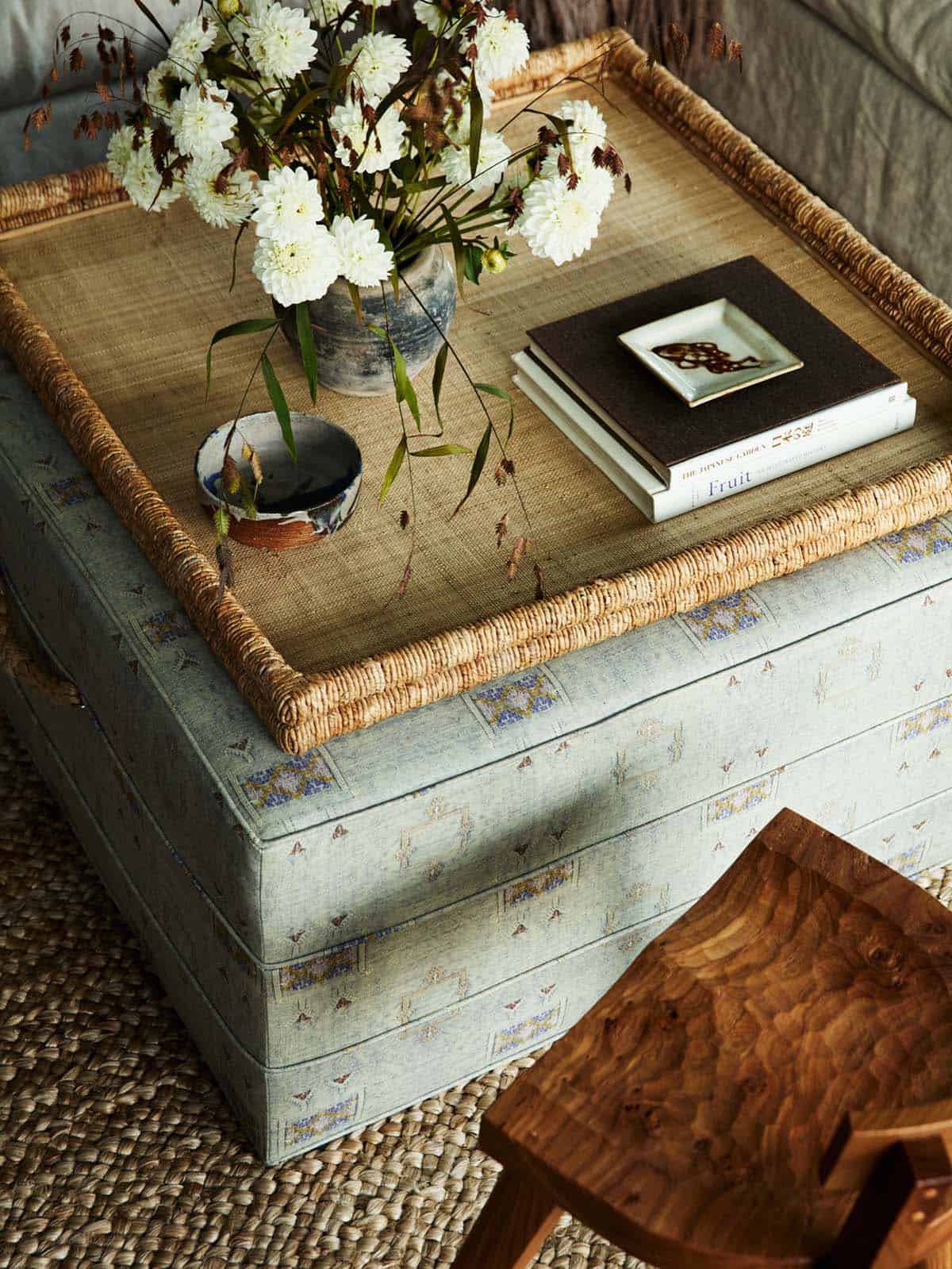 Woven tray ottoman styled with dried flowers and stacked books
