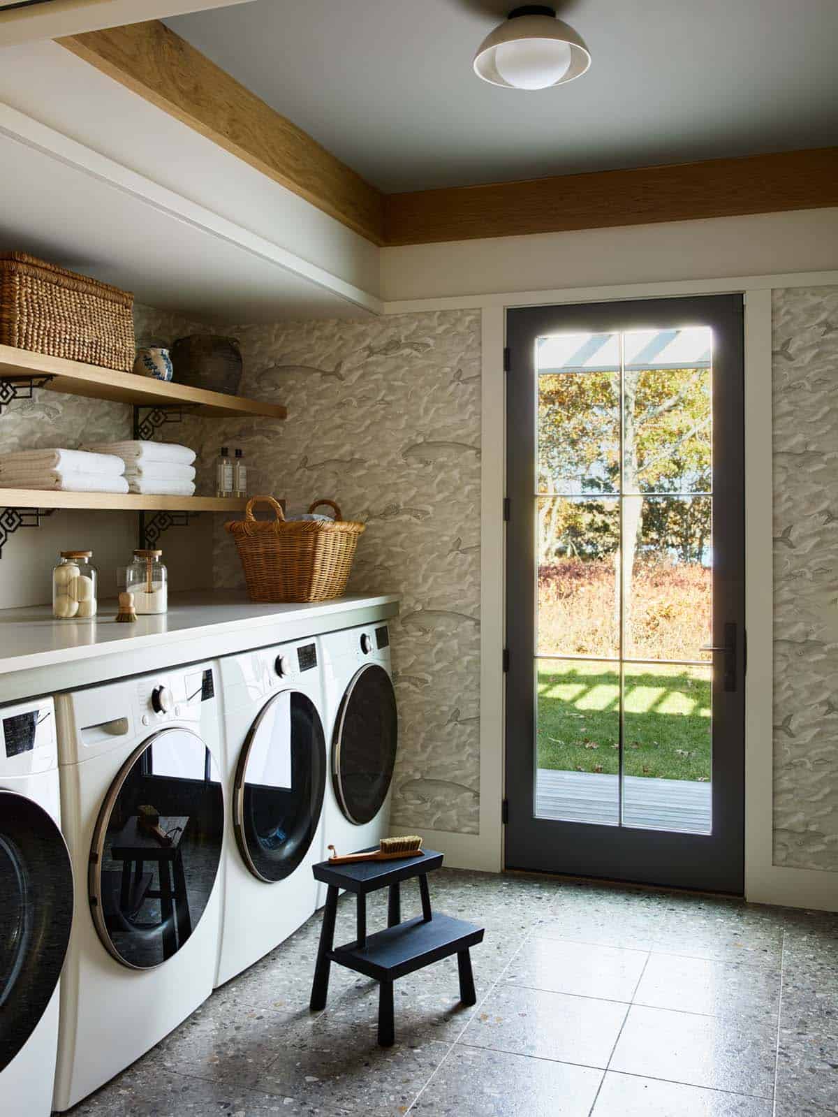 Laundry room with whale print wallpaper and glass door to the yard