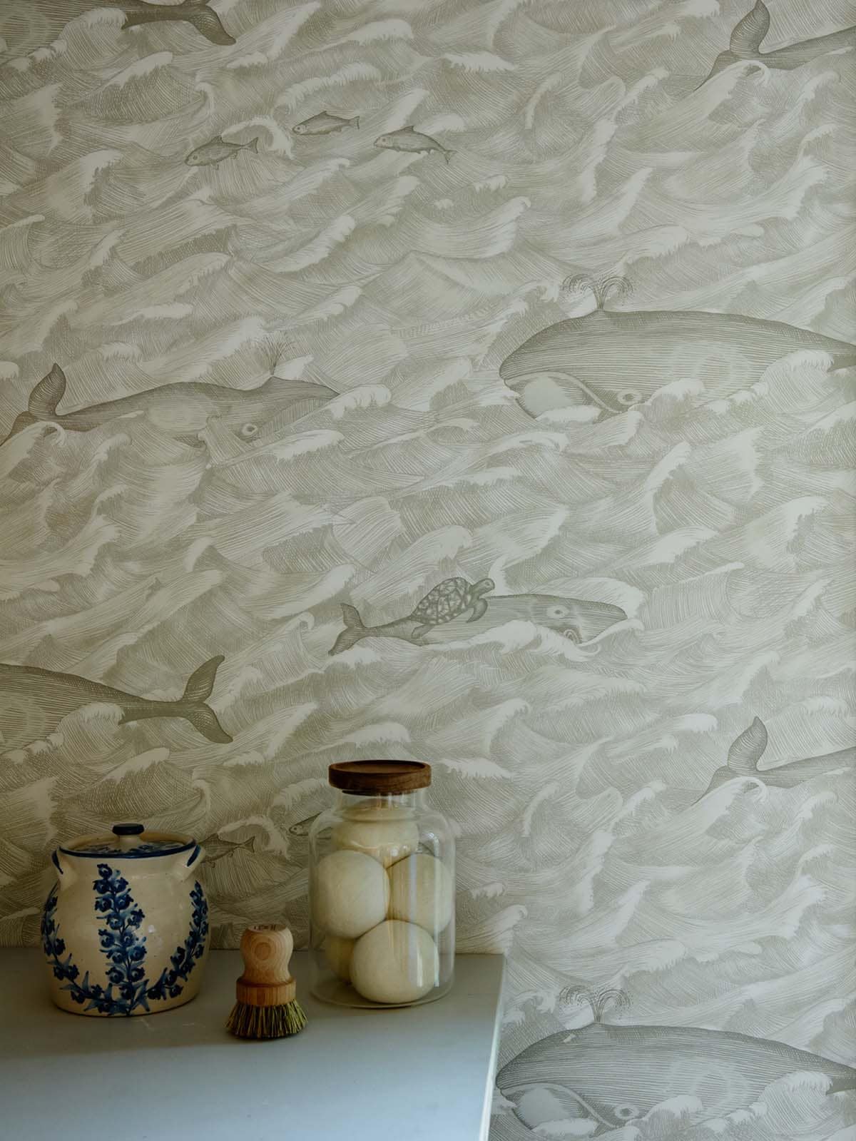Whale and wave print wallpaper detail above a marble countertop