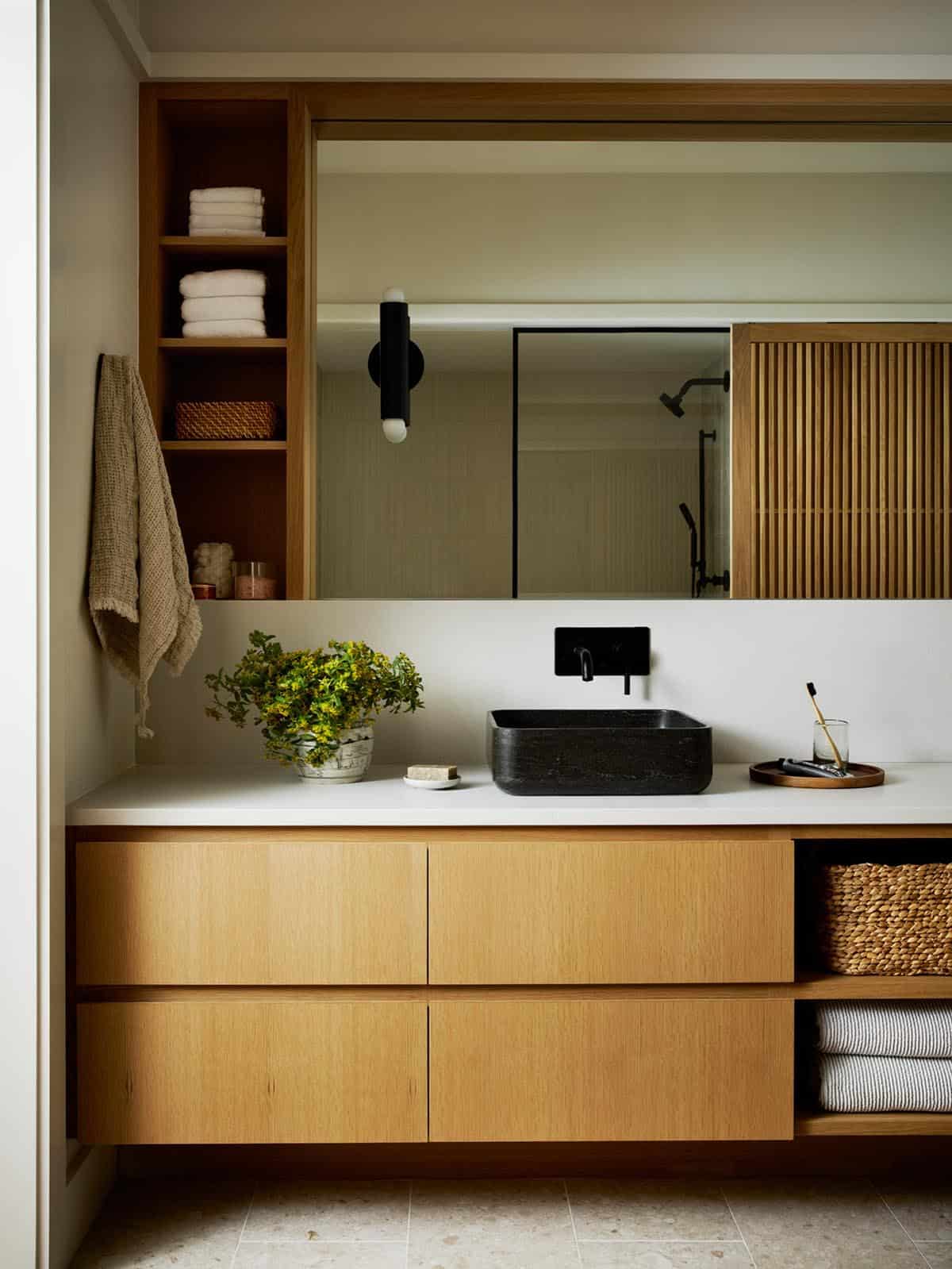 Bathroom vanity with black stone sink and slatted wood sliding door