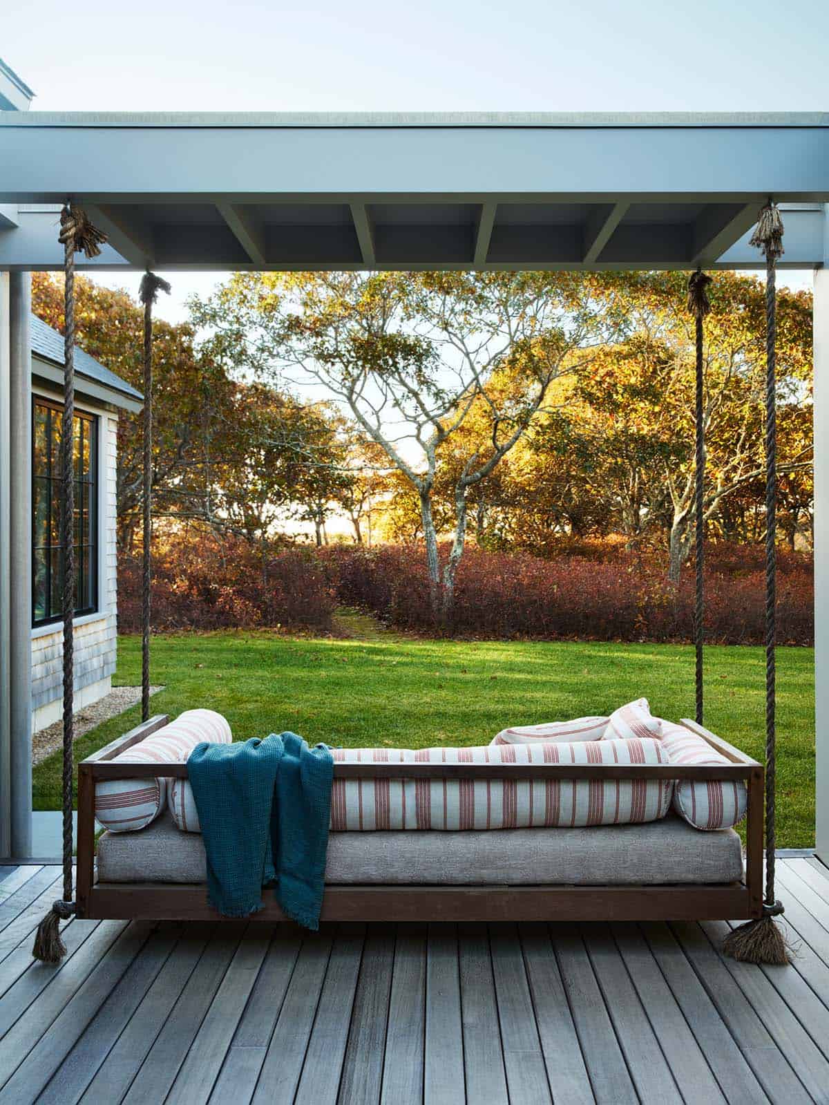 Rope-hung daybed swing overlooking the lawn and autumn tree line