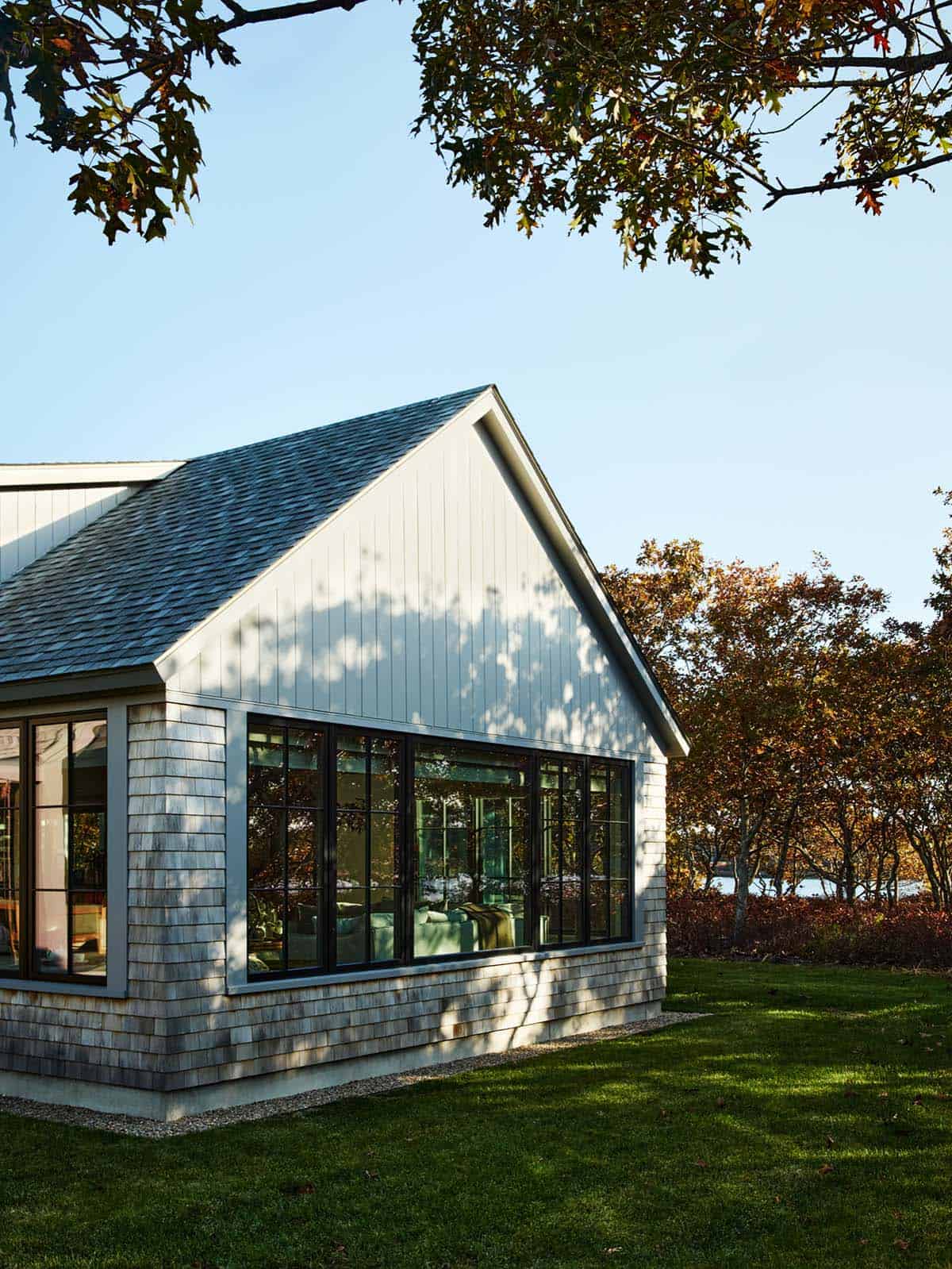 Exterior corner view of the shingled home framed by autumn trees