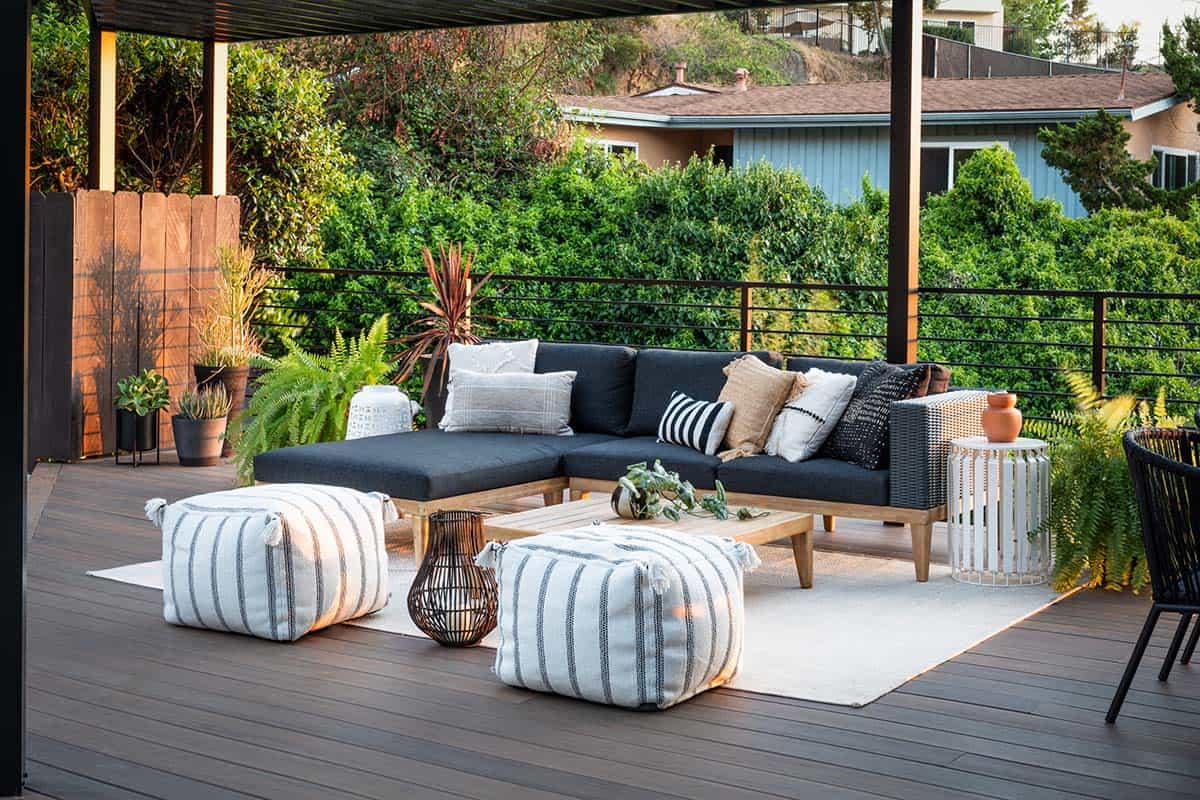 Mid-century covered deck in San Diego, California with TimberTech decking, charcoal sectional, and striped poufs