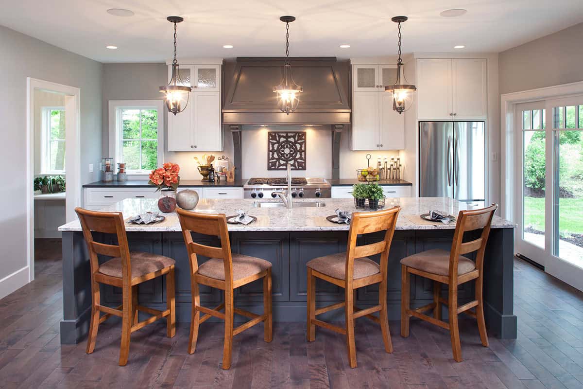 Kitchen island with granite countertop, bar stool seating, and gray range hood