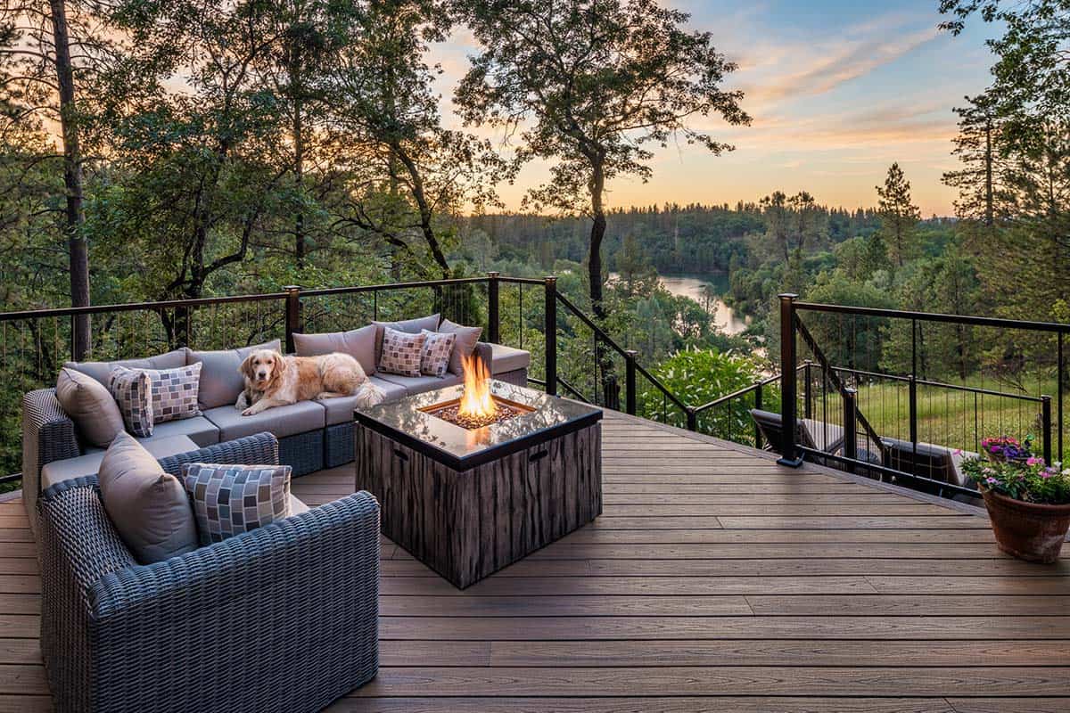Deck in Meadow Vista, California with wicker sectional, fire table, dog, and river valley view