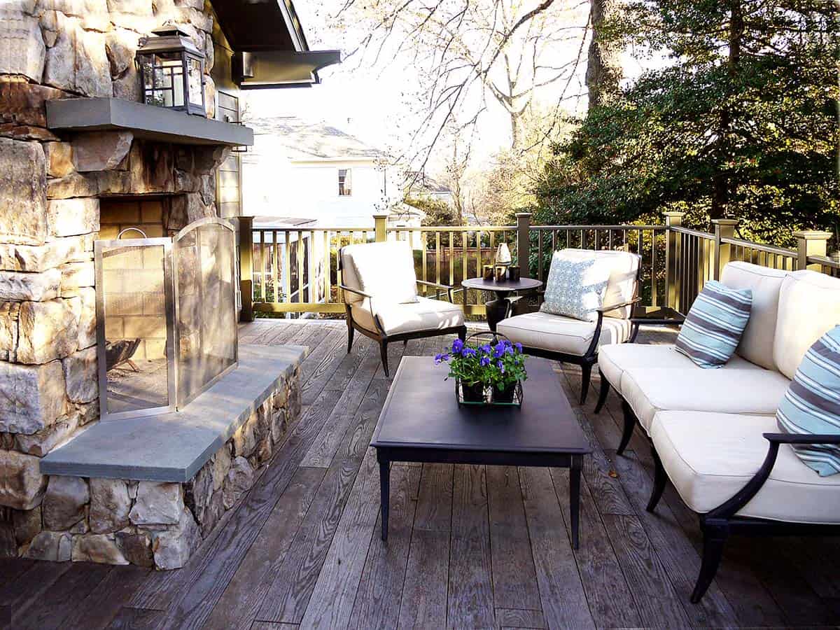 Deck seating area with stone fireplace, cream cushioned chairs, and striped throw pillows