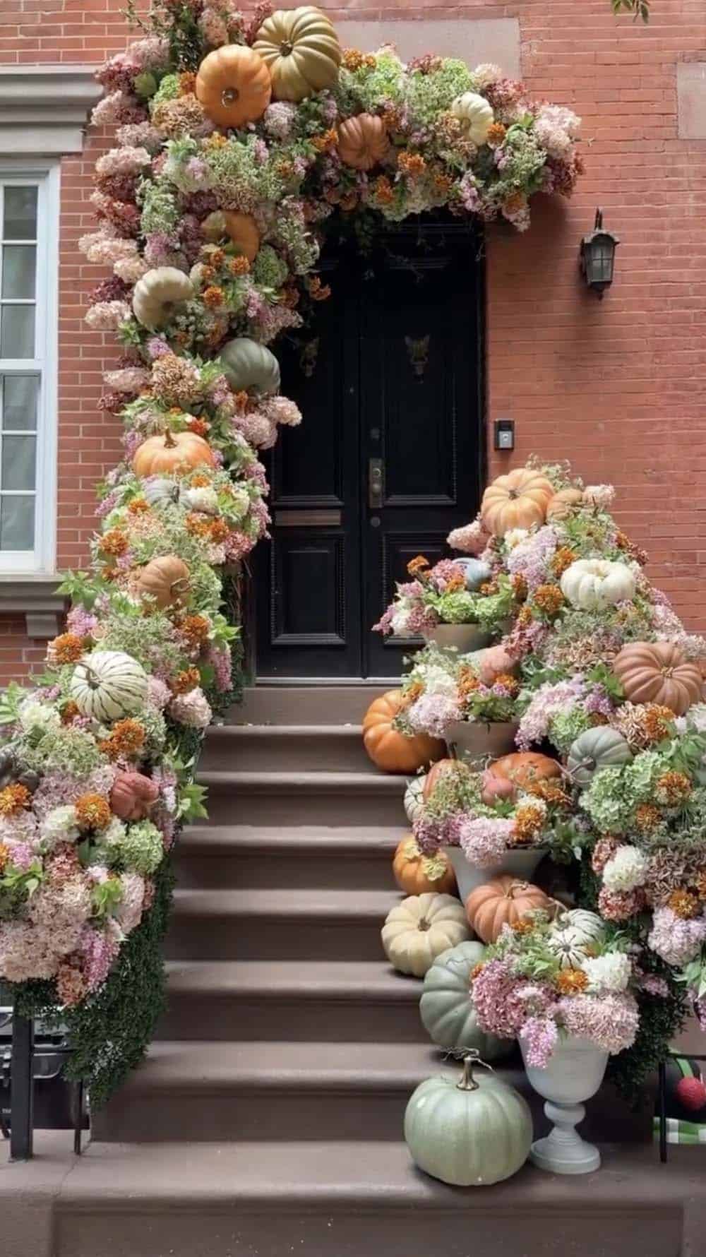 Brownstone stoop railings covered in floral garland and pumpkins