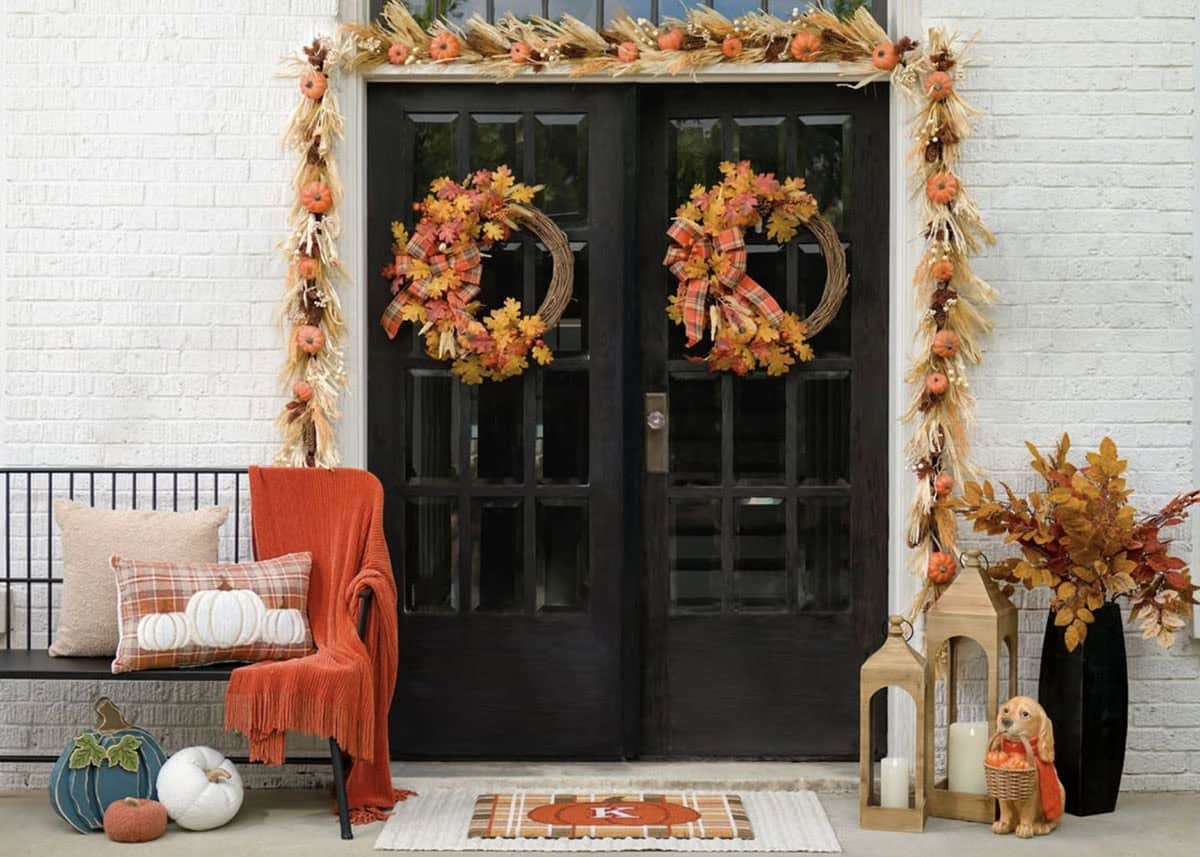 Black double doors framed with a pumpkin and wheat garland and wreaths