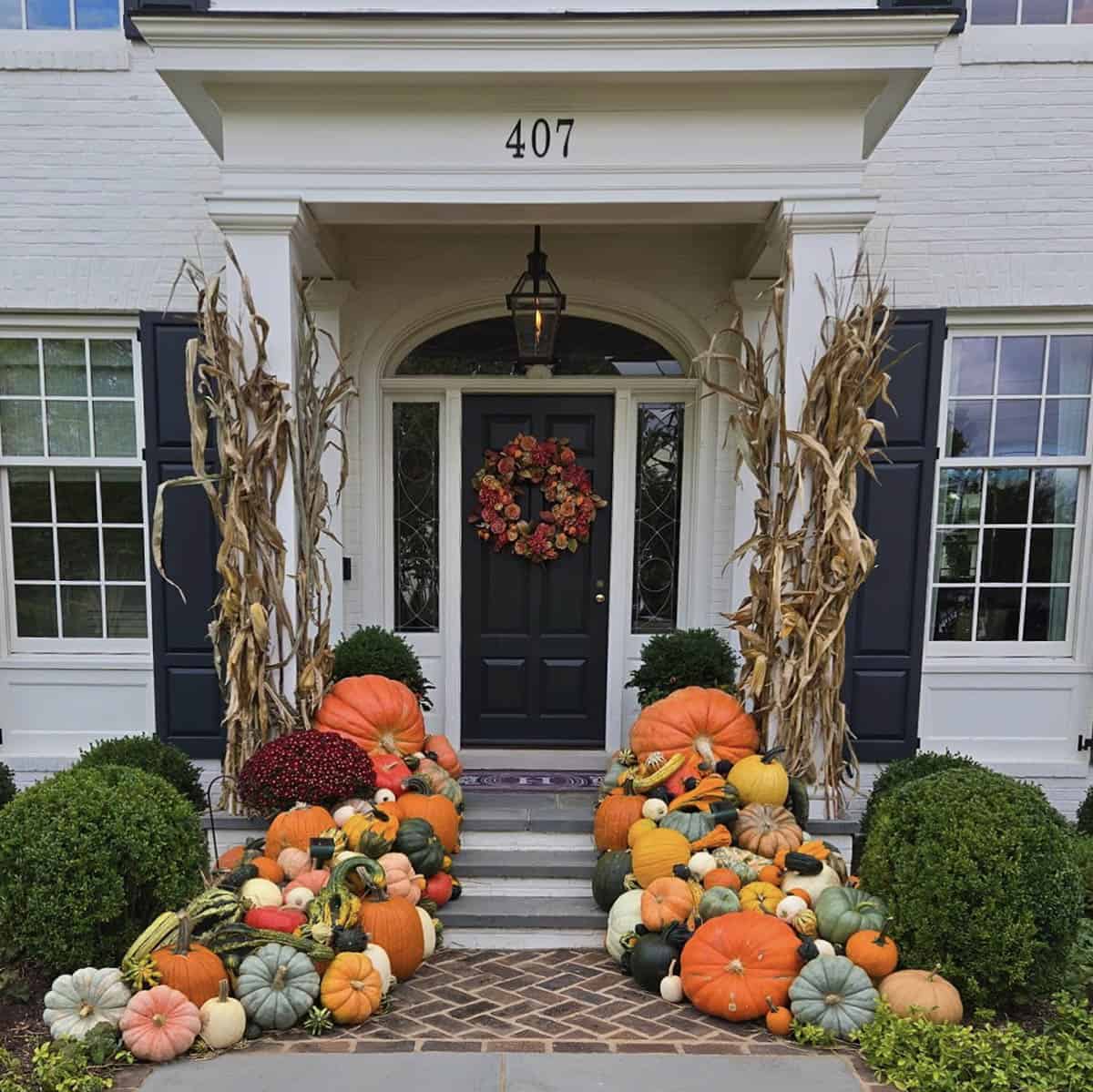 Front walkway lined with a pile of pumpkins, gourds and cornstalks