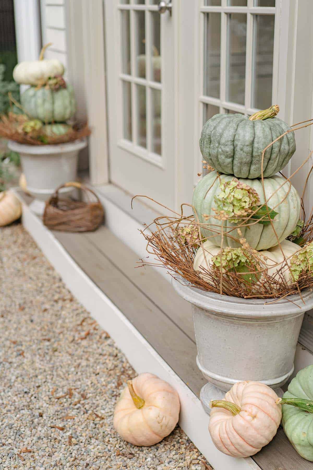Glazed ceramic urn with stacked heirloom pumpkins and dried hydrangea