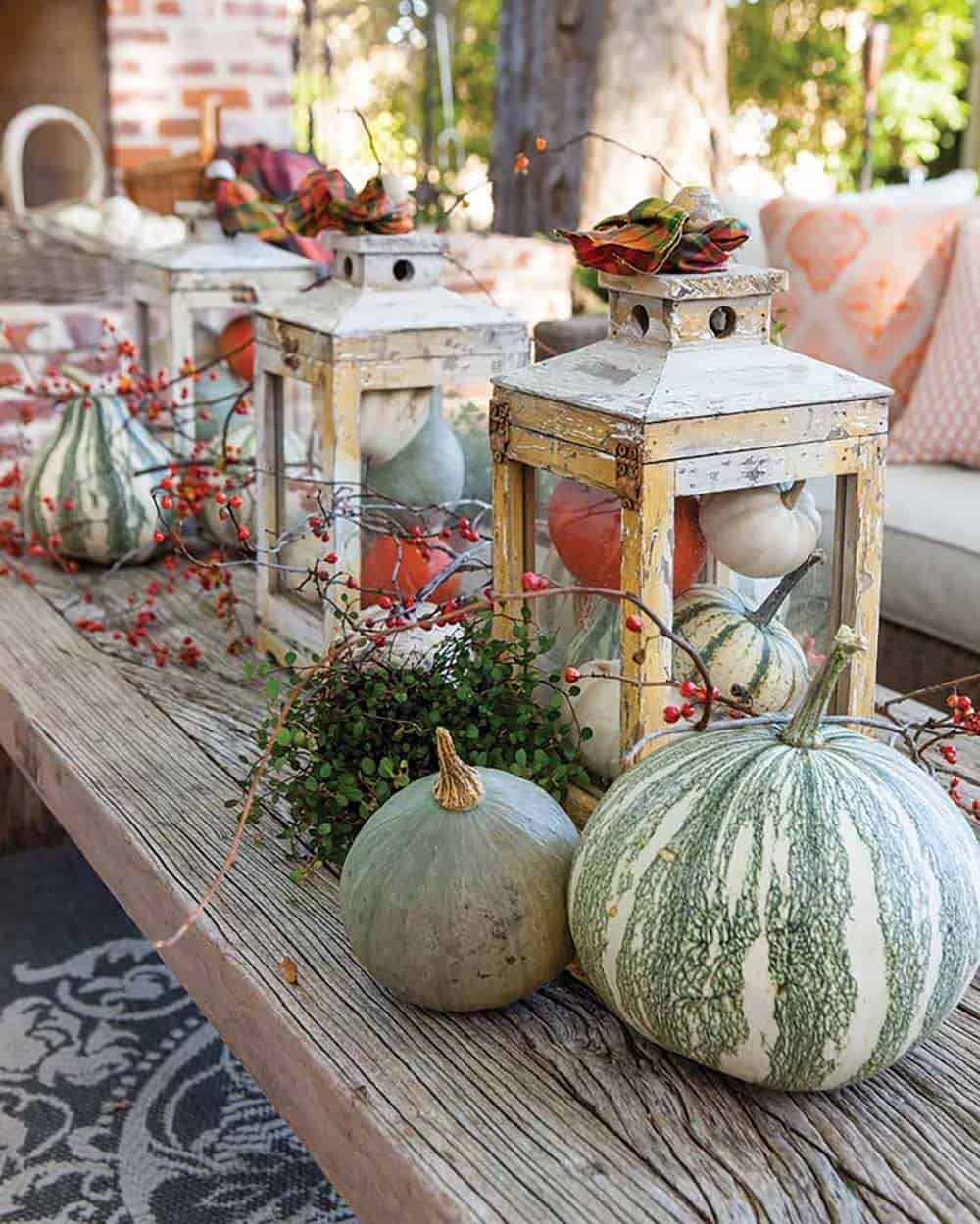 Rustic lanterns filled with mini pumpkins on a wooden bench
