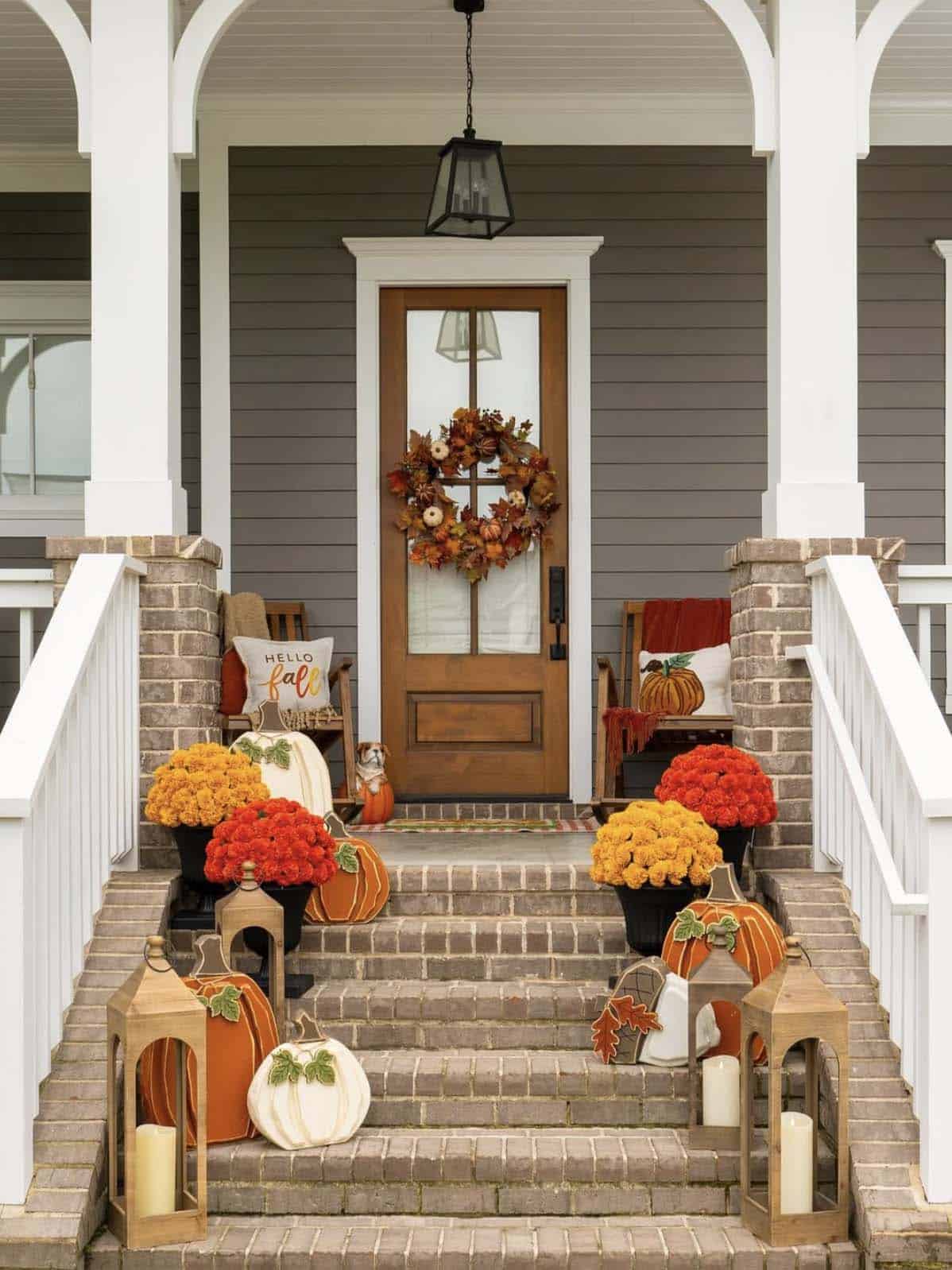 Fall porch steps decorated with mums, pumpkins, lanterns and a leaf wreath