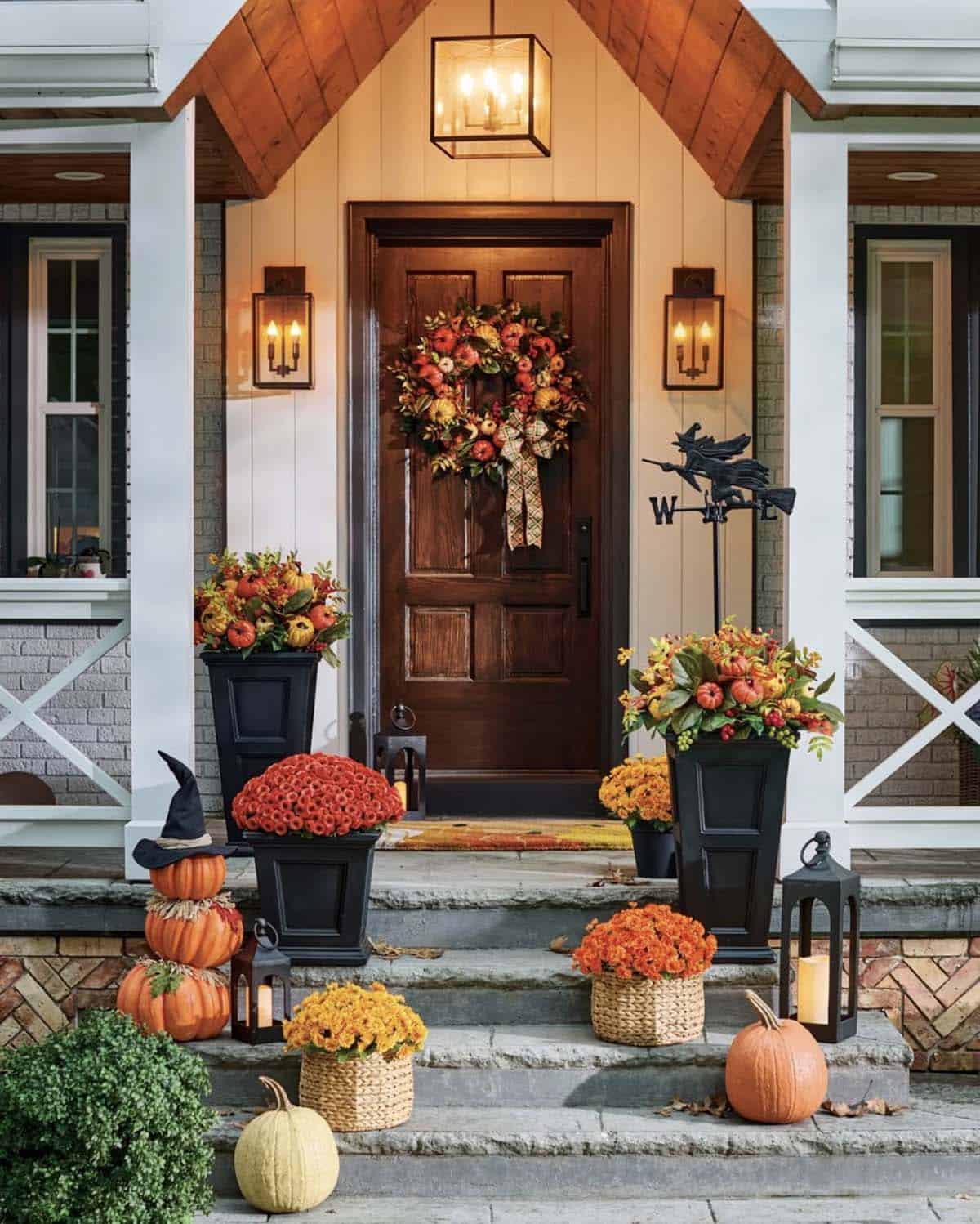 Front porch with a witch hat pumpkin stack, mums and lanterns
