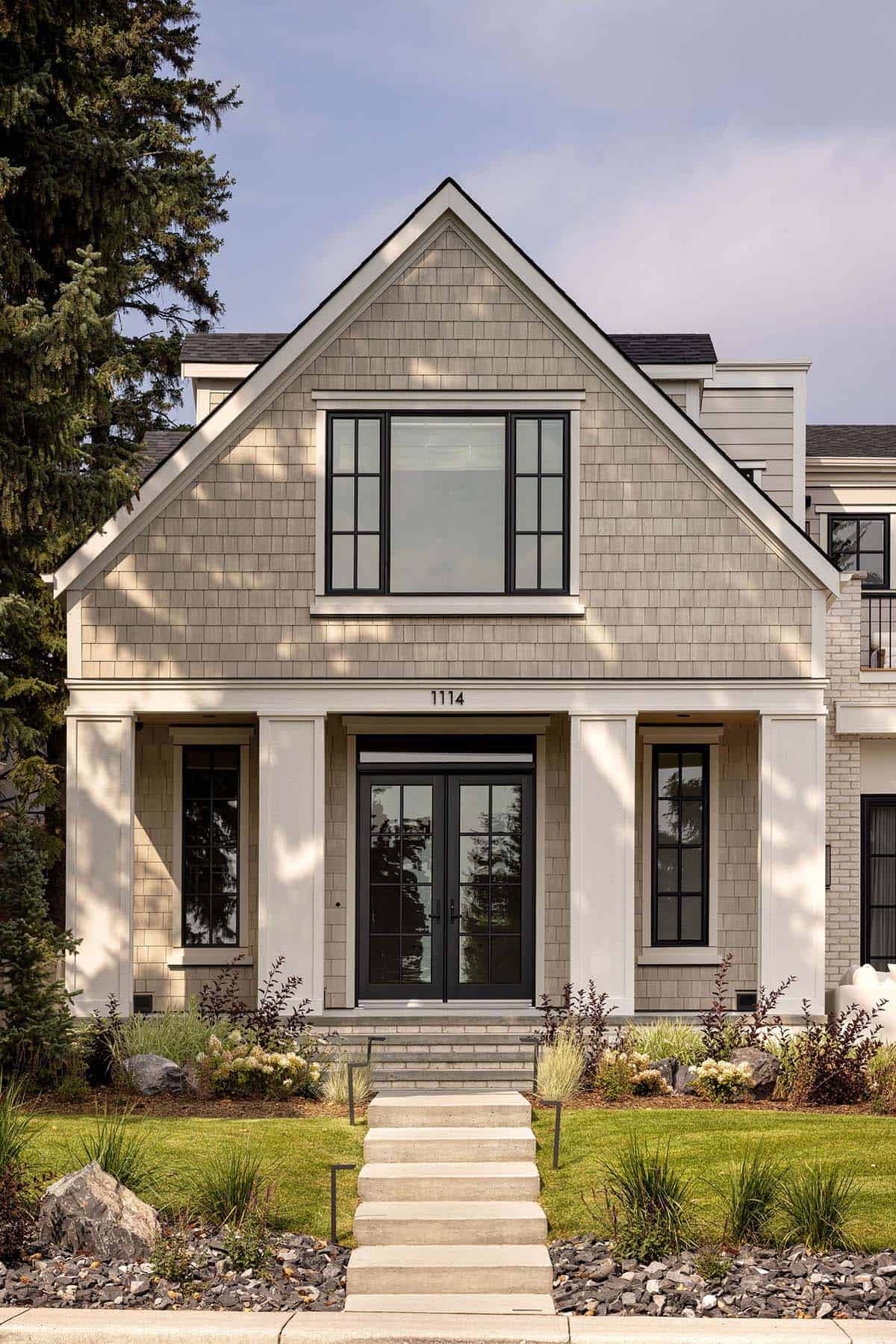 Hamptons-style shingle home exterior with gabled roof, black-framed windows, and covered front porch entrance