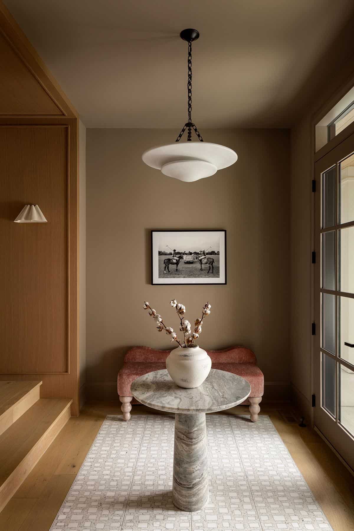 Foyer with pink velvet bench, marble pedestal table, and dome pendant light