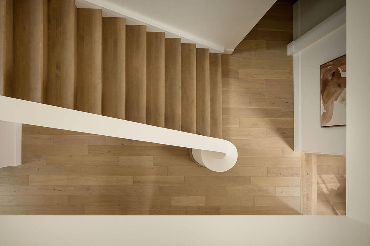 Overhead view of wooden staircase with curved white handrail