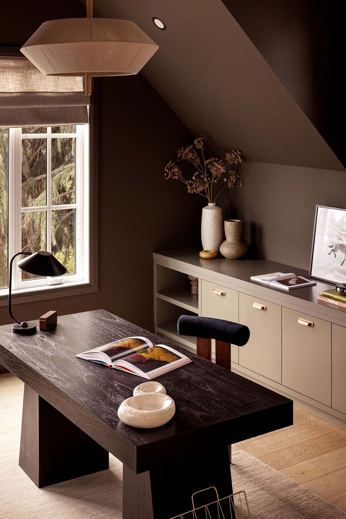 Close-up of home office desk with woven pendant light and gray built-in cabinetry