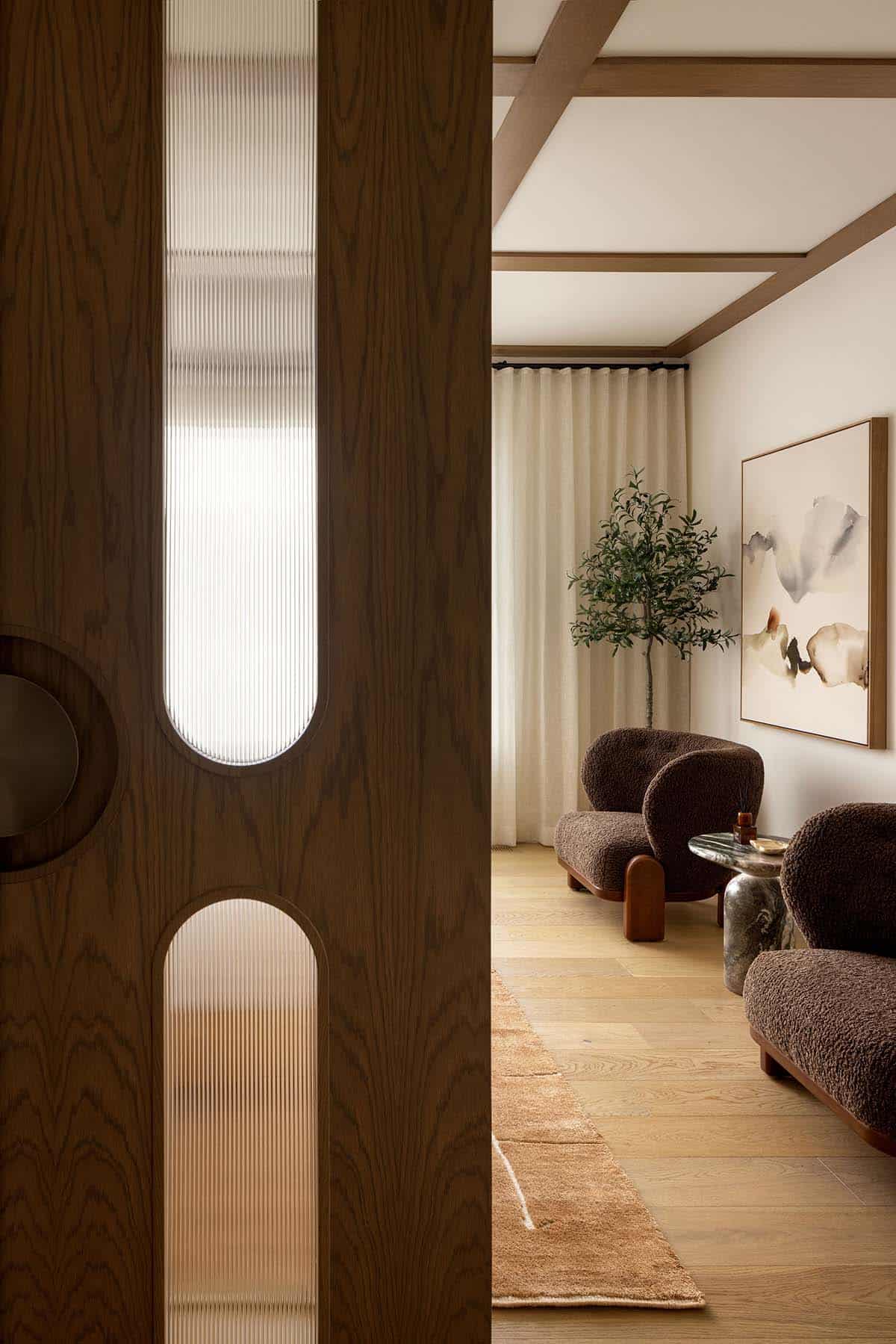 Reeded-glass wood door opening into a living room with boucle chairs